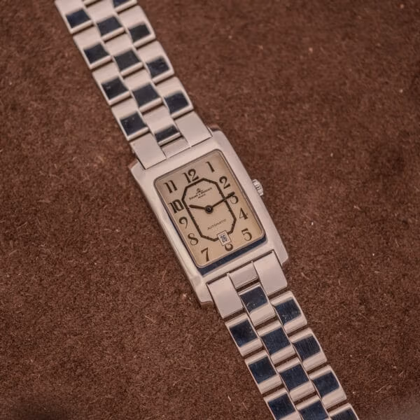 Baume Mercier Hampton Automatic MV045120 angled three-quarter view, rectangular stainless steel case with signed crown at three on suede backdrop.