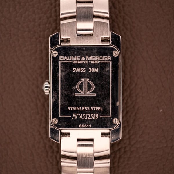 Back of a Baume Mercier Hampton 65511 Quartz Stainless Steel watch with engraved brand details, model reference, and serial number.