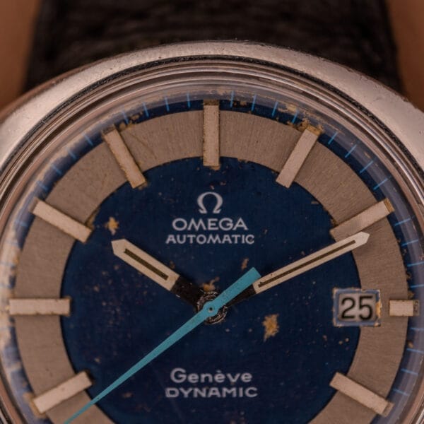 Close-up of an Omega Automatic Geneve Dynamic Ref. 166.107 Cal. 1421 watch, showcasing a blue dial, silver markers, and visible signs of wear.