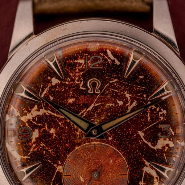 Close-up of an Omega Automatic 2491 "Pre-Seamaster" Tropical Dial Cal. 28.10 RA, featuring a heavily patinated, speckled brown dial with gold hour markers—an iconic vintage design.