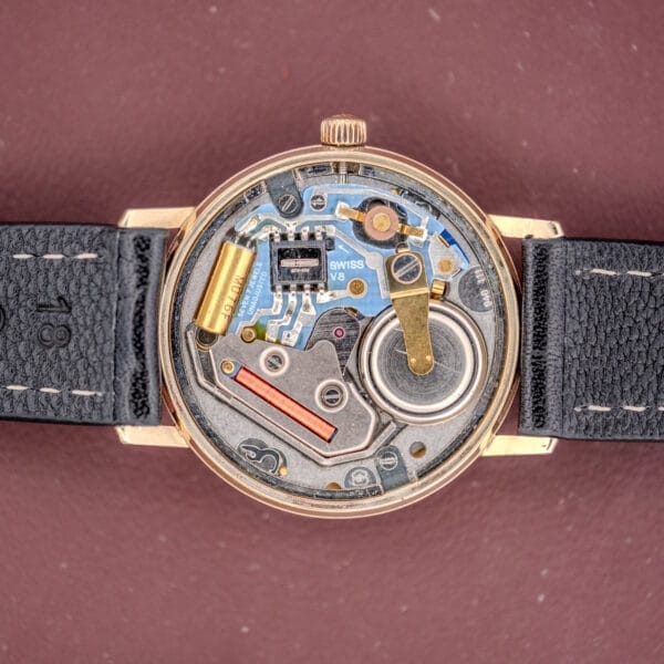 Open watch case displaying intricate mechanical and electronic components, with a Champagne Dial and black leather straps. The Girard Perregaux Quartz Date 3696 Cal. ETA 940 showcases refined craftsmanship and a precise date function.