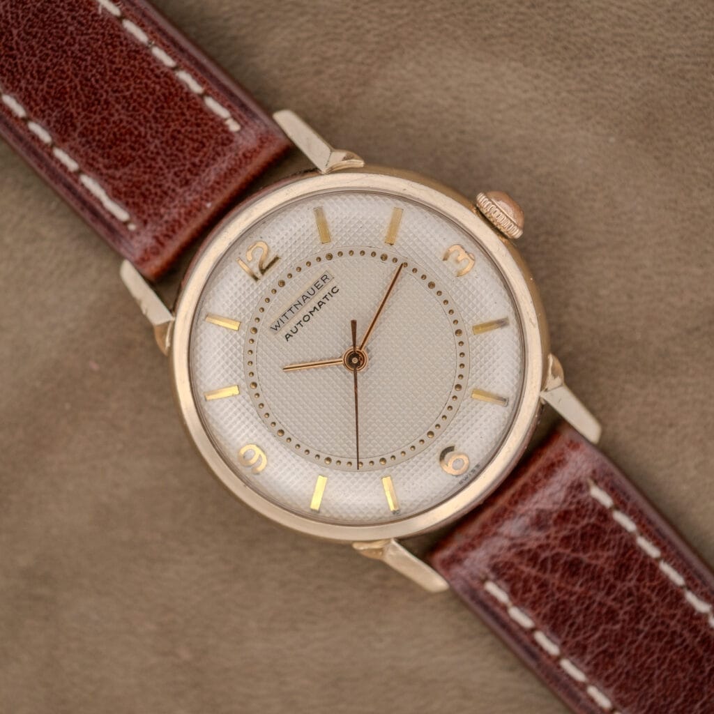 A vintage Wittnauer Automatic Waffle Dial Ref. 2023 wristwatch with a 10k GF case, Cal. 11ARB, brown leather strap, and gold hour markers and hands.