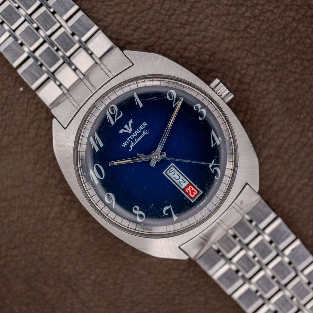 A Wittnauer Automatic Day/Date Ref. 3503 wristwatch with a stainless steel band and blue spider dial, shown on brown leather.