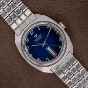 A Wittnauer Automatic Day/Date Ref. 3503 wristwatch with a stainless steel band and blue spider dial, shown on brown leather.