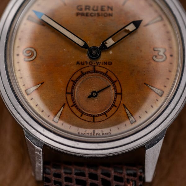 Close-up of a Gruen Precision Auto-Wind wristwatch with a copper dial and large hour markers, housed in a classic stainless steel case, Cal. 400.