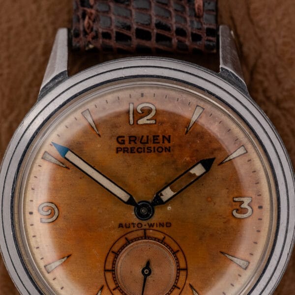 Close-up of a vintage Gruen Precision Auto-Wind wristwatch featuring a copper dial, stainless steel case, and textured leather strap, powered by Cal. 400.