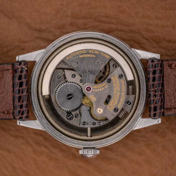 A close-up of the Gruen Precision Auto-Wind Copper Dial in Stainless Steel Cal. 400, featuring its exposed mechanical movement with visible gears and text, paired with a brown leather strap.