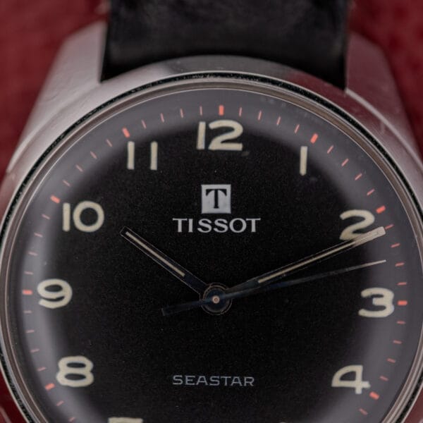 Close-up of a Tissot Seastar Ref. 42568 with a matte black dial and stainless steel case, Cal. 781-1, showing the time at 10:10:11 against a vibrant red background.