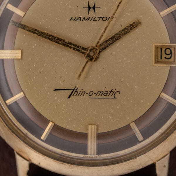 Close-up of the Hamilton Thin-O-Matic Brown & Gold Dial, showcasing its Automatic Cal. 624 movement, date display, and textured brown and gold dial.