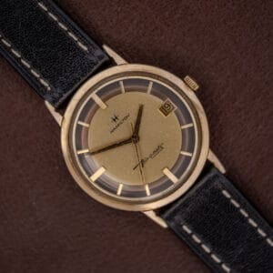Hamilton Thin-O-Matic Brown & Gold Dial Automatic Cal. 624 wristwatch with black leather strap, displayed on a brown background.
