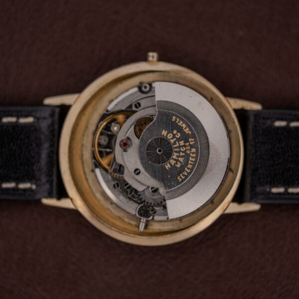 Close-up of the Hamilton Thin-O-Matic Brown & Gold Dial Automatic Cal. 624, showcasing its intricate gears and black leather strap.