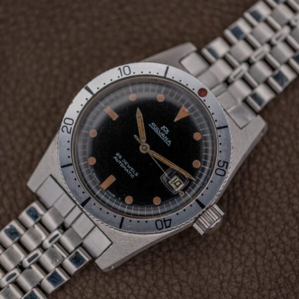 A vintage Silvana 25 Jewels Automatic Skin Diver wristwatch with Cal. 2472 movement and black dial, displayed on a textured brown surface.