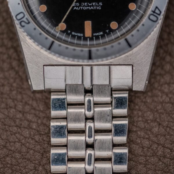 Close-up of a Silvana 25 Jewels Automatic Skin Diver Cal. 2472 Black Dial wristwatch with a metal band, resting on a brown textured surface.