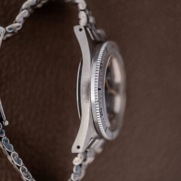 Side view of a Silvana 25 Jewels Automatic Skin Diver Cal. 2472 Black Dial wristwatch with a metal band, shown against a brown textured background.