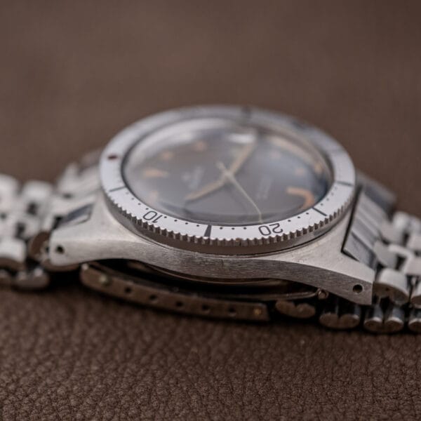 A close-up side view of the Silvana 25 Jewels Automatic Skin Diver Cal. 2472 Black Dial wristwatch with a metal band, resting on a brown textured surface.