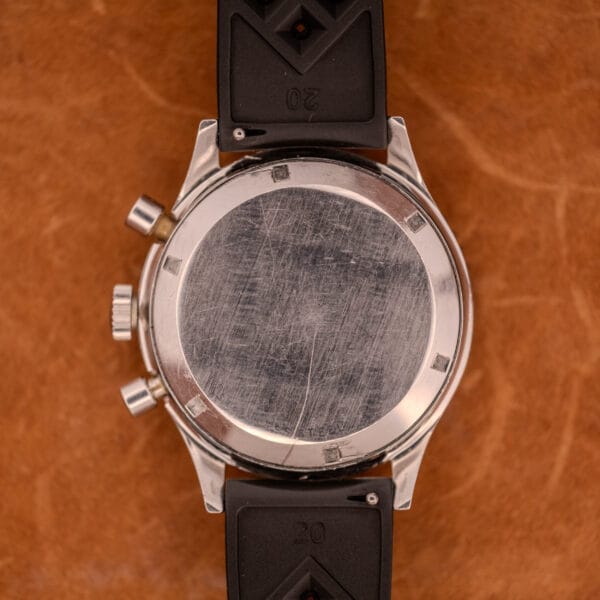 A scratched metal caseback and black rubber strap rest on brown leather—a Wittnauer Professional Chronograph Ref. 7004 Landeron 248, known for its classic style and reliable movement.