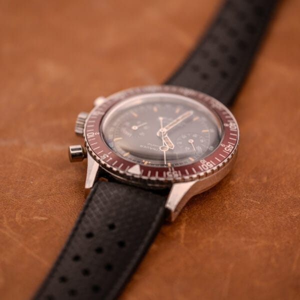 A Wittnauer Professional Chronograph Ref. 7004 Landeron 248 with a black perforated strap rests elegantly on a brown leather surface.