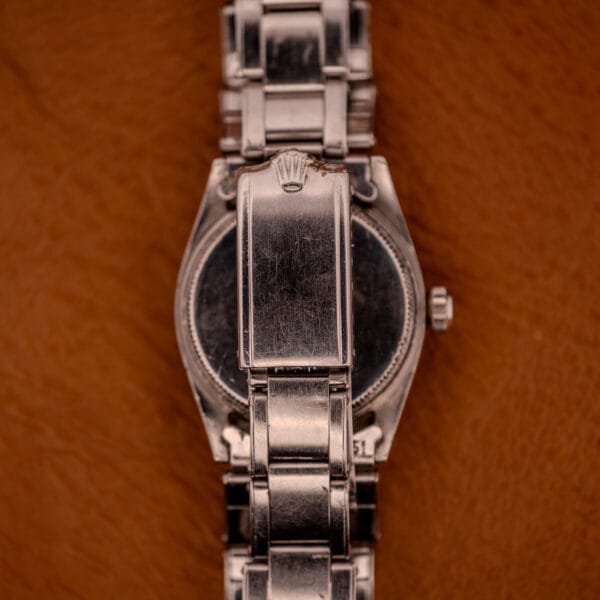 Close-up of the Rolex Oyster Speedking Ref. 6420 Stainless Steel Black Dial clasp, set against a brown textured background.