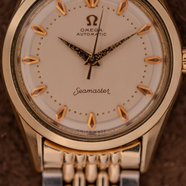 Close-up of an Omega Seamaster "De Luxe" Ref. 2802 with Automatic Cal. 471 movement, gold hour markers, and a metal band.