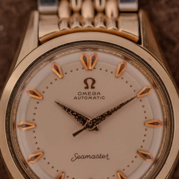 Close-up of an Omega Seamaster "De Luxe" Ref. 2802 wristwatch featuring Automatic Cal. 471 movement, gold hour markers, and gold hands.