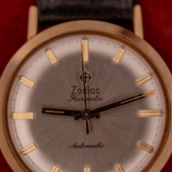 Close-up of a Zodiac Hermetic Sunburst Dial 10k Gold Filled Case Automatic wristwatch, featuring gold hour markers and black hands.