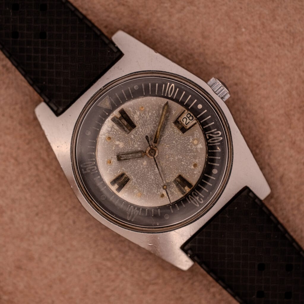 The Aquastar 1701 Skin Diver 200 Meters Automatic features a worn silver dial, black bezel, tropic rubber strap, and displays the date as the 28th.