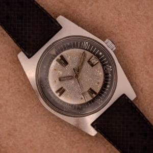 Aquastar 1701 Skin Diver front view, mottled silver-grey patina dial with applied baton markers, sword hands, date at 3, internal black dive bezel.