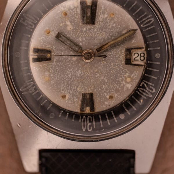 Close-up of the Aquastar 1701 Skin Diver 200 Meters Automatic watch with a worn dial, black hour markers, date set to 28, and classic tropic rubber strap.