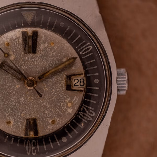 Aquastar 1701 Skin Diver dial close-up showing signed crown, internal rotating bezel, applied steel baton markers and date window at 3 o'clock.