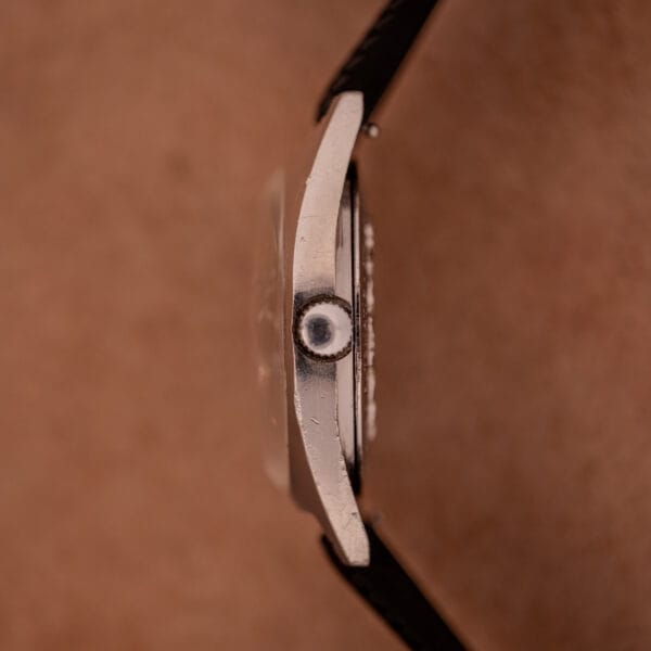 Side view of the Aquastar 1701 Skin Diver 200 Meters Automatic wristwatch with a scratched metal case and black Tropic Rubber Strap set against a brown background.