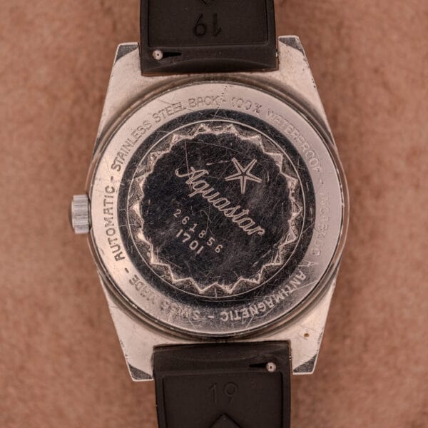Close-up of the back of an Aquastar 1701 Skin Diver 200 Meters Automatic watch with engraved text and a Tropic Rubber Strap.