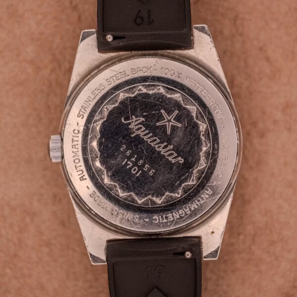 Caseback of Aquastar 1701 with engraved outer ring reading AUTOMATIC STAINLESS STEEL BACK 100% WATERPROOF INCABLOC ANTIMAGNETIC SWISS MADE, serial 261856.