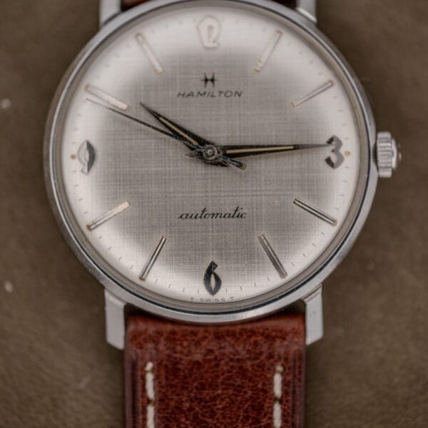 A Hamilton Automatic Silver Linen Dial Stainless Steel Cal. 689A watch with a brown leather strap, showing the time as 10:09.