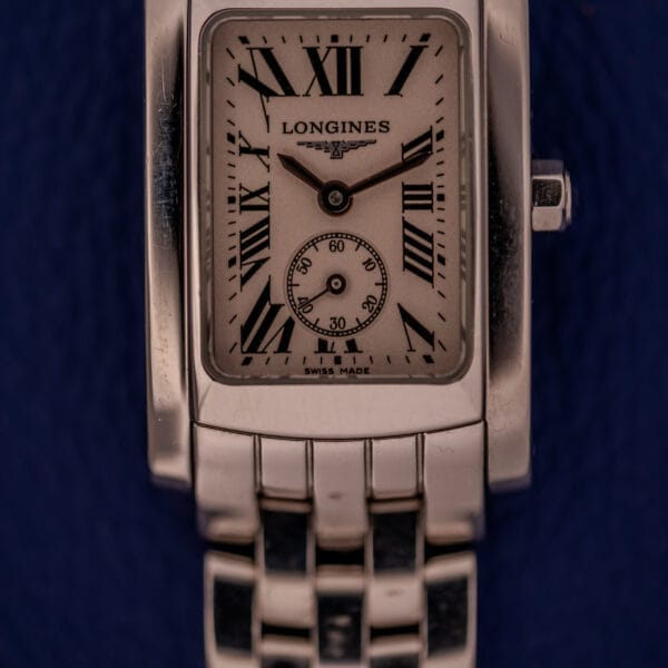 The Longines Dolce Vita L5.155.4 features a stainless steel tank case and Roman numerals, displayed against a dark blue background.