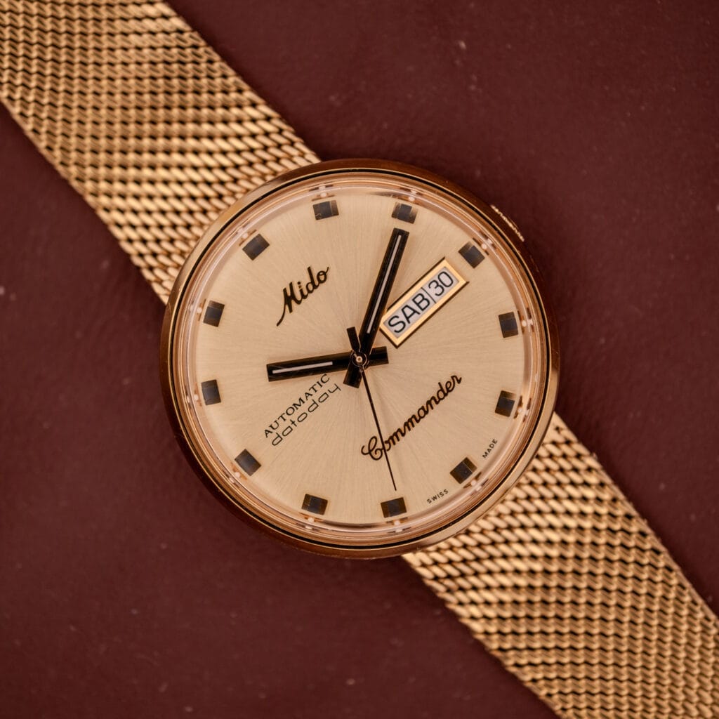 The Mido Commander Automatic Datoday Ref. 8429 features a Milanese strap, beige dial, and an automatic Datoday display showing SAT 30.