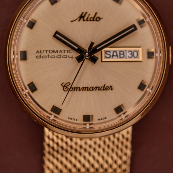Close-up of the Mido Commander Automatic Datoday Ref. 8429 with a Milanese strap, displaying day and date as SAB 30.