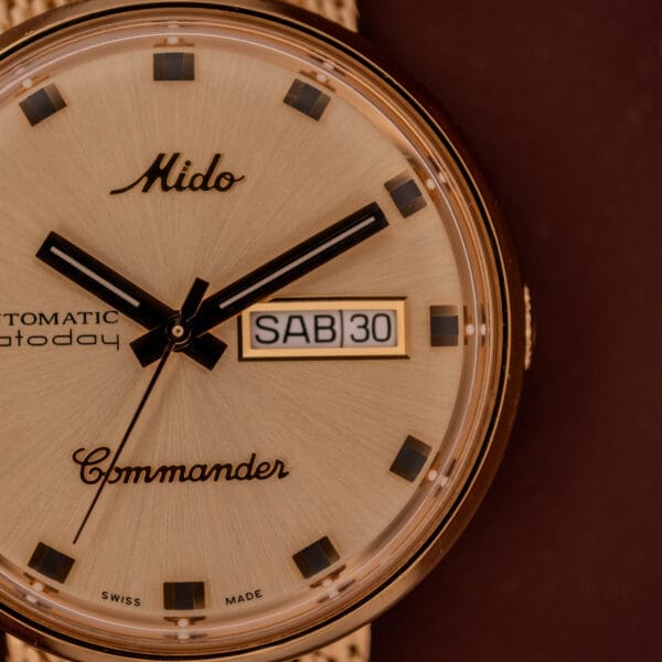 Close-up of the Mido Commander Automatic Datoday Ref. 8429 with a Milanese strap, showing the time at 10:10 and the date as Saturday, 30th.