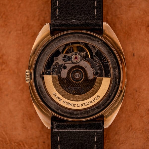 A close-up of the Mido Automatic Multi Star Datoday Cal. 1819 Ref. 6929300 watch’s exposed mechanical movement with a black leather strap.