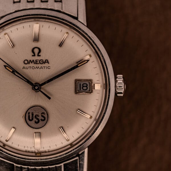 Close-up of an Omega Automatic Ref. 166.020 for U.S. Steel Presentation Watch, featuring a date set to 18 and "USS" on the dial.