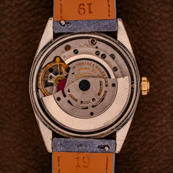 Close-up of the exposed mechanical movement inside a vintage Rolex Oyster Perpetual 1024 with a 14k gold-capped case and sunburst dial, showcasing intricate gears and engravings.