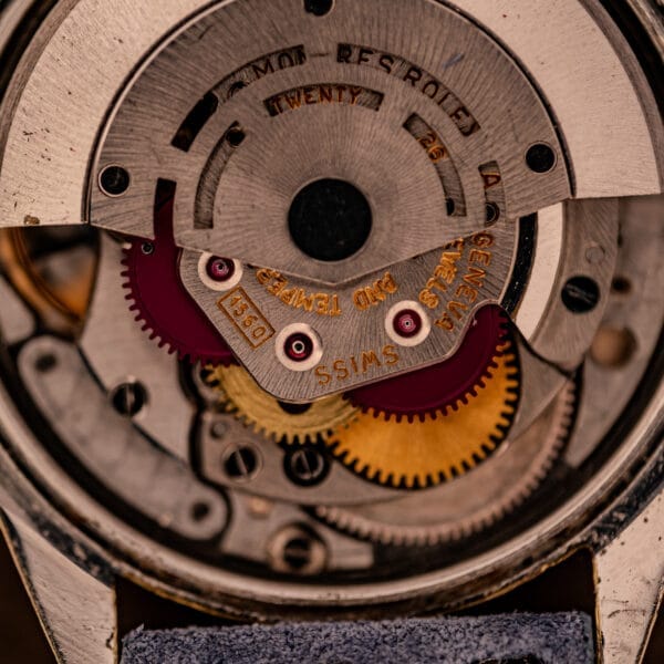 Close-up of intricate gears inside the Rolex Oyster Perpetual 1024, showcasing 14k gold-capped details and a sunburst dial, highlighting Swiss mechanical watch craftsmanship.