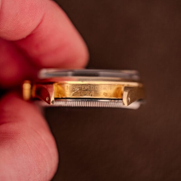 Close-up of a hand holding a Rolex Oyster Perpetual 1024 14k Gold Capped & Sunburst Dial, highlighting the engraved text on the side of the watch case.