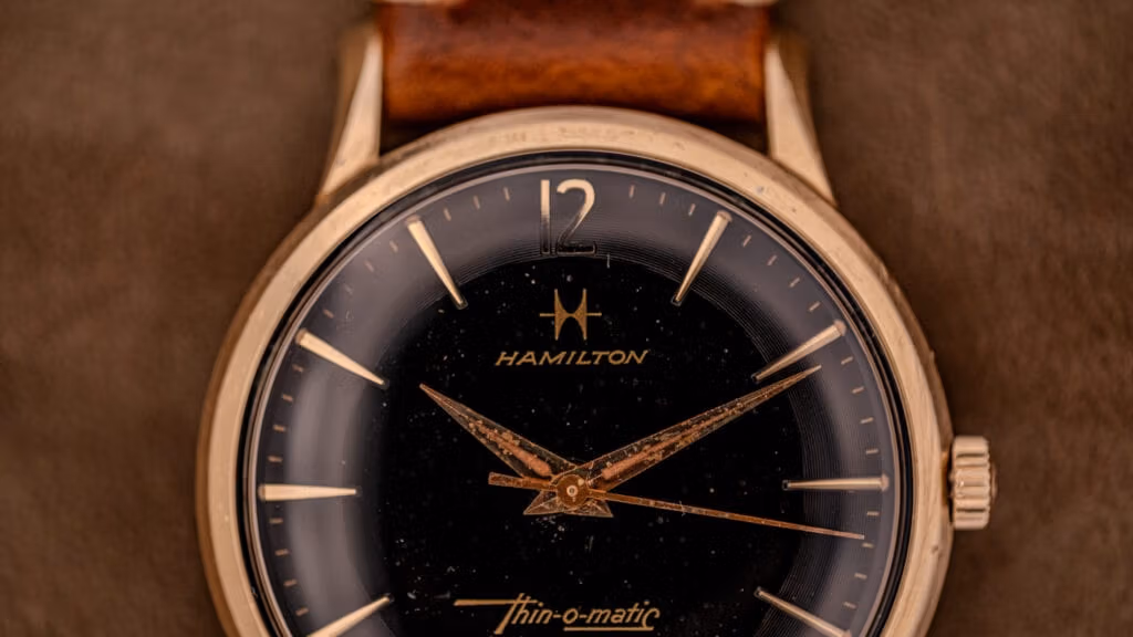 Close-up of a vintage Hamilton Thin-o-matic wristwatch, featuring a brown leather strap and elegant gold details.