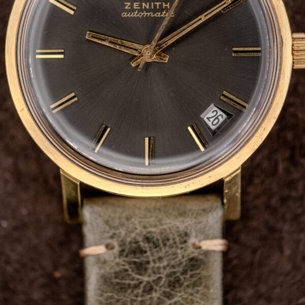 Close-up of a Zenith Automatic Date Charcoal Sunburst Dial Cal. 2542 PC wristwatch with a gold case and date display set to the 26th.
