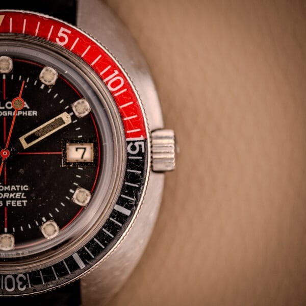 Close-up of the Bulova Oceanographer Automatic Snorkel 714, featuring the Red Cross Hair Dial, red and black bezel, and date window.