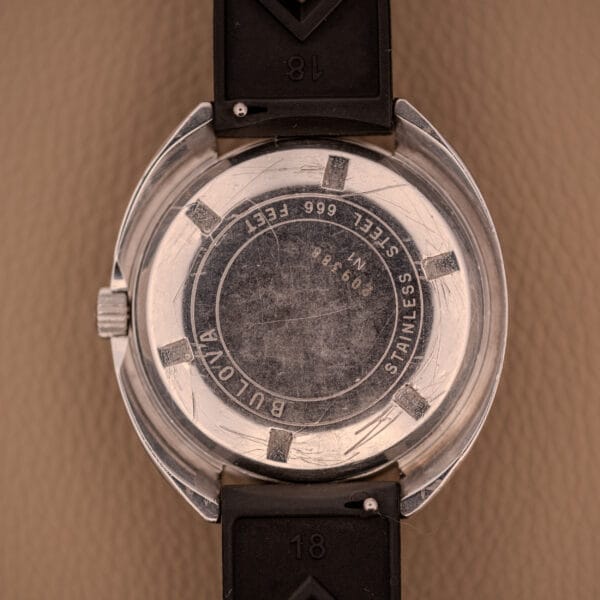 Back view of a Bulova Oceanographer Automatic Snorkel 714 Red Cross Hair Dial watch with a scratched stainless steel case, black rubber strap, and signature Snorkel design details.