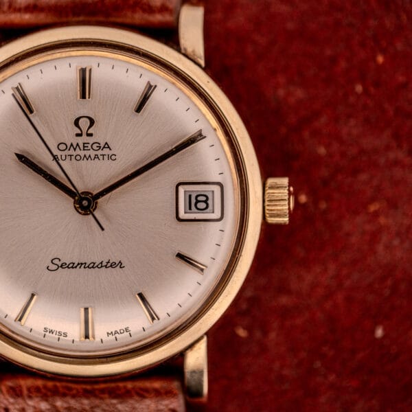Close-up of an Omega Automatic Seamaster Date Ref. KM 6323 wristwatch, featuring a Cal. 563 movement, date display, and brown leather strap.