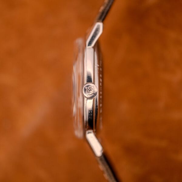 Close-up side view of the Zodiac Glorious Automatic Ref. 702-917 wristwatch, featuring a decorative crown and stainless steel case with Cal. 70-72 movement, set against a brown background.