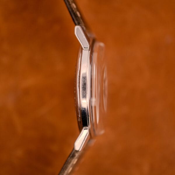 Side view of the Zodiac Glorious Automatic Ref. 702-917 Stainless Steel Cal. 70-72 case and crystal against a blurred brown background.