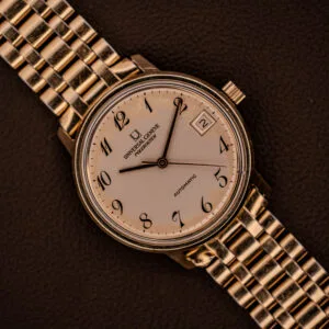 Universal Geneve Polerouter Date with white Arabic numerals dial, automatic Cal 215 movement, and classic style. Displayed on a textured brown surface.